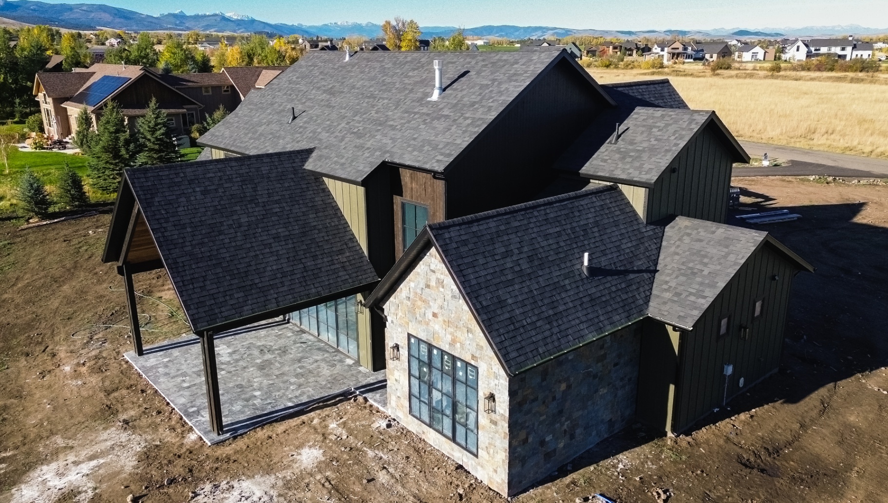 Stone and board-and-batten home with new roof — mountain backdrop